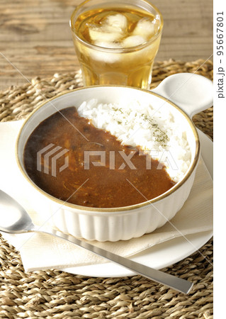 耐熱皿に盛られた熱々チーズカレーライスとお茶 95667801