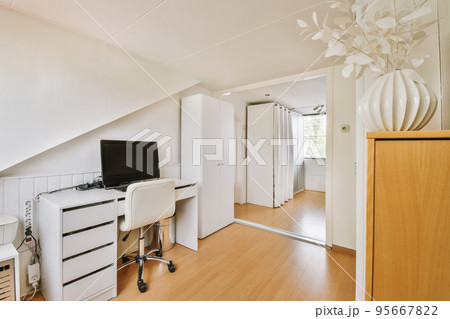 Comfortable chair placed near desk with computer monitors and whiteboard in light workplace in modern apartment Comfortable chair placed near desk with computer monitors and whiteboard in light workplace in modern apartment 95667822
