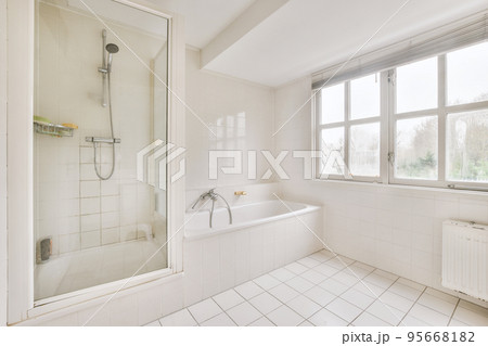 Contemporary bathroom with bathtub and glass shower cabin with light beige tile and white ceiling 95668182