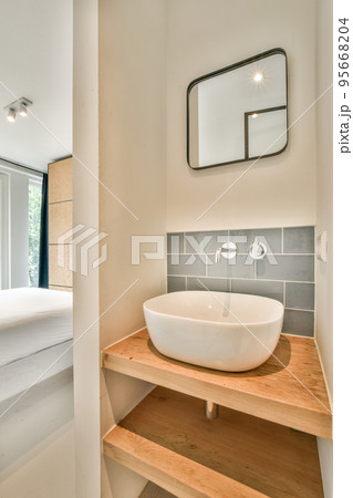 Tiled shower cabin with glass door located near sink and mirror in light restroom in contemporary apartment 95668204