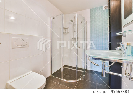 Flush toilet located between sink and shower in small tiled bathroom of contemporary apartment Flush toilet located between sink and shower in small tiled bathroom of contemporary apartment 95668301