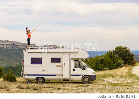 Woman traveling with caravan, taking photo from rv roof Woman traveling with caravan, taking photo from rv roof 95668341