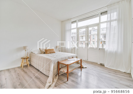 Comfortable bed and soft carpet in spacious bedroom with interior in minimal style 95668656