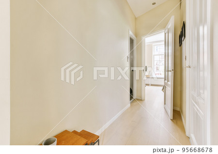 Light narrow hallway with many doors in white walls and glowing lamp over lumber floor 95668678