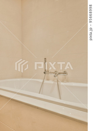 Modern home interior design of white bathroom with open bathtub and shower separated from toilet by partition wall Modern home interior design of white bathroom with open bathtub and shower separated from toilet by partition wall 95668998