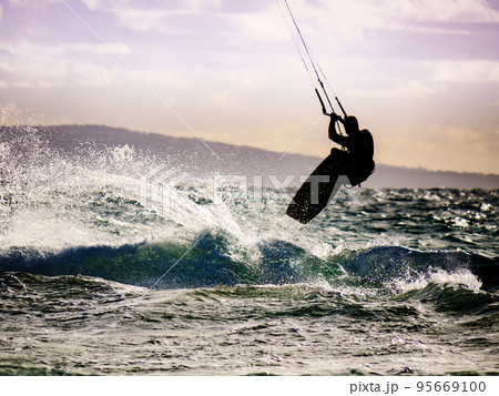 Kite surfer riding waves. Kiteboarding sport. 95669100