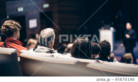 Speaker giving a talk in conference hall at business event. Rear view of unrecognizable people in audience at the conference hall. Business and entrepreneurship concept. Speaker giving a talk in conference hall at business event. Rear view of unrecognizable people in audience at the conference hall. Business and entrepreneurship concept. 95670190
