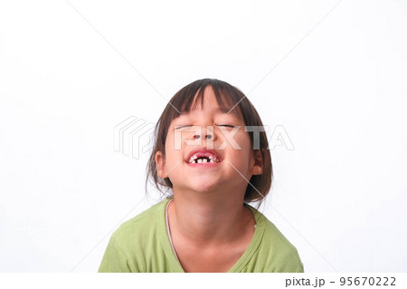 Portrait of an Asian girl with broken upper baby teeth and first permanent teeth. Friendly little girl showing her broken teeth isolated on white background. Portrait of an Asian girl with broken upper baby teeth and first permanent teeth. Friendly little girl showing her broken teeth isolated on white background. 95670222