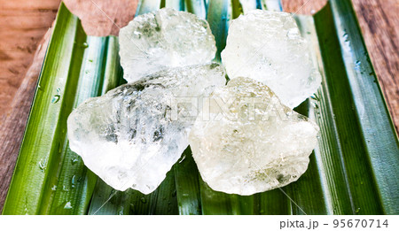 Crystal clear alum cubes or Potassium alum on green leaf Chemical compound substance Concept for beauty spa and underarm treatment industrial Crystal clear alum cubes or Potassium alum on green leaf Chemical compound substance Concept for beauty spa and underarm treatment industrial 95670714