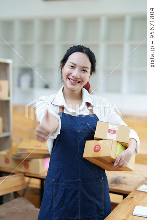 Starting small business entrepreneur of independent Asian woman smiling using computer laptop with cheerful success of online marketing package box items and SME delivery concept. 95671804