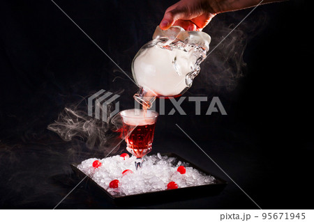 The bartender pours an alcoholic smoky cocktail from a bottle in the form of a skull 95671945