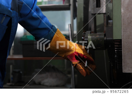A worker in the production of bearings. An unrecognizable personality. The worker controls the machine for the manufacture of bearings. Harmful production. 95672265