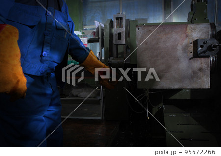 The worker controls the machine for the manufacture of bearings. Worker in the production of bearings. An unrecognizable personality. Harmful production. 95672266