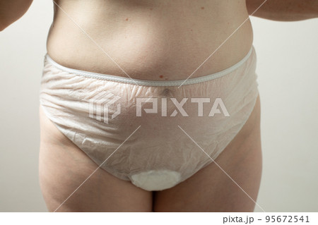 Female postpartum belly in disposable underpants, hygiene 95672541