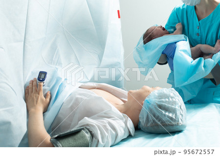 Nurse holds newborn baby close to mother in hospital Nurse holds newborn baby close to mother in hospital 95672557