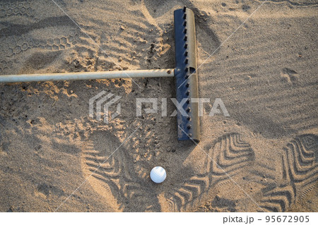 Golf concept. Golf ball and rake sand on bunker in beautiful golf course at sunset background 95672905