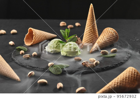 Gourmet chocolate and pistachio ice cream served on a stone slate over a black background. 95672932