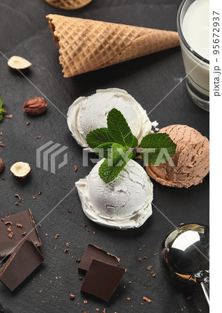 Gourmet creamy and chocolate ice cream served on a stone slate over a black background. 95672937