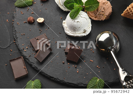 Gourmet creamy and chocolate ice cream served on a stone slate over a black background. 95672942