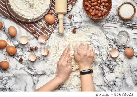 Close-up shot. Top view of a baker cook place, hands are working with a raw dough on the marble table background. Close-up shot. Top view of a baker cook place, hands are working with a raw dough on the marble table background. 95673022