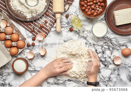 Close-up shot. Top view of a baker cook place, hands are working with a raw dough on the marble table background. 95673066