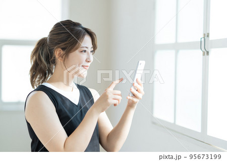スマートフォンを操作する若い女性。 95673199