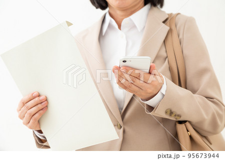 書類の入った封筒とスマホを持つミドル女性のビジネスウーマン 95673944