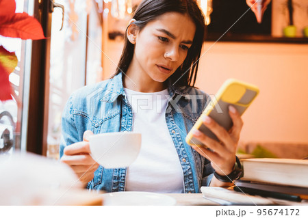 Concerned young woman reading bad news on her smartphone 95674172