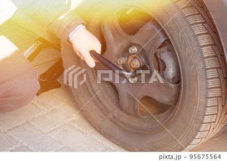 Man is changing wheel after a car break down. Damaged car tyre. Wheel balancing or repair and change car tire. Auto repair concept. Sunlight. Man is changing wheel after a car break down. Damaged car tyre. Wheel balancing or repair and change car tire. Auto repair concept. Sunlight. 95675564