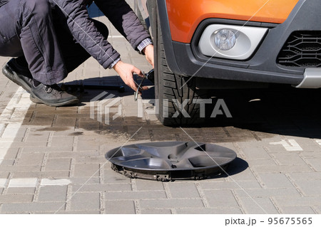 Man is changing wheel after a car break down. Damaged car tyre. Wheel balancing or repair and change car tire. Auto repair concept. Man is changing wheel after a car break down. Damaged car tyre. Wheel balancing or repair and change car tire. Auto repair concept. 95675565