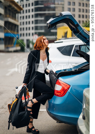 A woman puts things in the car A woman puts things in the car 95676538
