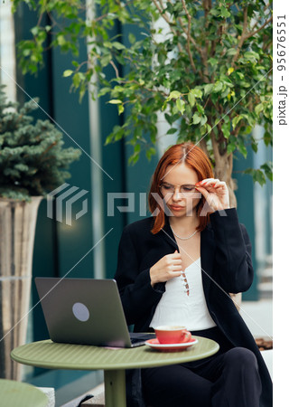 Beautiful woman working on laptop at outdoors cafe Beautiful woman working on laptop at outdoors cafe 95676551