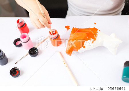 a little girl paints a toy fox made of clay. DIY concept a little girl paints a toy fox made of clay. DIY concept 95676641