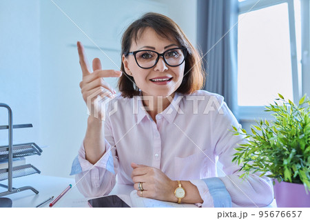 Webcam view of talking mature woman sitting at desk in home office 95676657