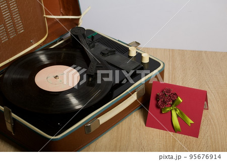 Vintage vinyl record player. Homemade greeting card. With decorative elements. Ribbons, flowers and leaves are attached to cardboard. 95676914