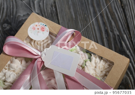 Homemade marshmallows in a gift box. Tied with ribbon. Zephyr flowers. On black pine boards. Taken from above. Homemade marshmallows in a gift box. Tied with ribbon. Zephyr flowers. On black pine boards. Taken from above. 95677035
