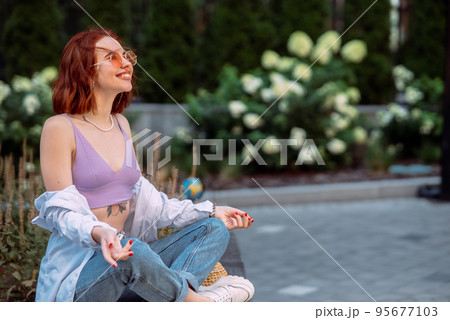 Young red-haired woman sitting in lotus position 95677103