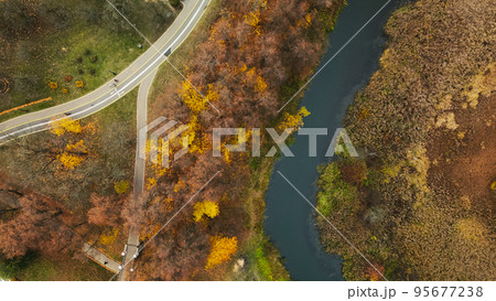 Autumn city park. Trees with colorful leaves. A cycle path winds between the trees. Autumn landscape. Aerial photography. Autumn city park. Trees with colorful leaves. A cycle path winds between the trees. Autumn landscape. Aerial photography. 95677238