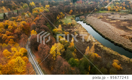 Autumn city park. Trees with colorful leaves. A cycle path winds between the trees. Autumn landscape. Aerial photography. 95677243