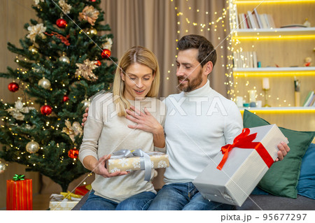 Middle aged couple exchanging gifts for christmas, family in love for christmas at home sitting on sofa at home. 95677297