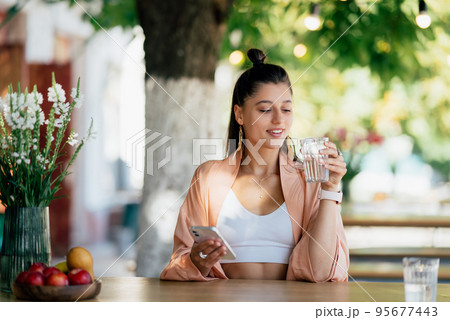 Young beautiful hipster woman sitting in veranda cafe in street. Young beautiful hipster woman sitting in veranda cafe in street. 95677443