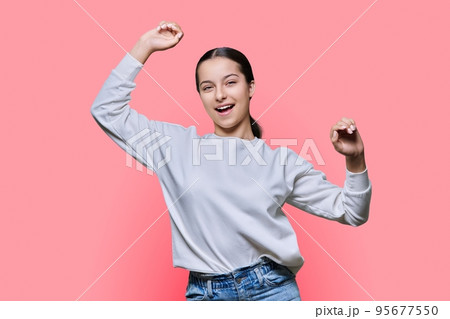 Cheerful dancing teenage girl on pink studio background 95677550