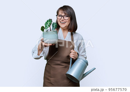 Woman in apron with watering can and potted plant, on white background 95677570