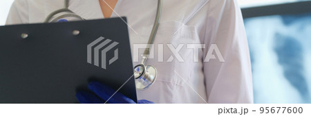 Radiologist checks x-ray image and holds clipboard in hands Radiologist checks x-ray image and holds clipboard in hands 95677600