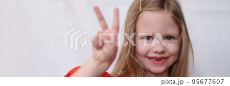 Smiling little girl without front teeth gesture two fingers up 95677607