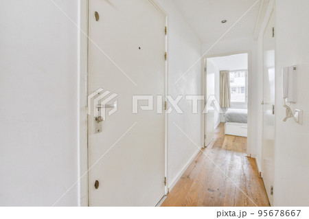 Light narrow hallway with many doors in white walls and glowing lamp over lumber floor 95678667