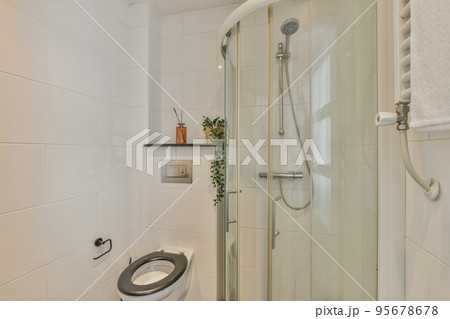 Tiled shower cabin with glass door located near sink and mirror in light restroom in contemporary apartment 95678678