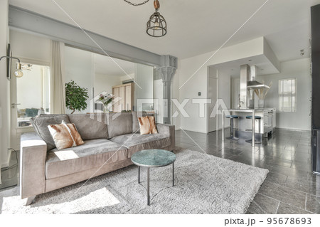 Table with chairs and flowers located near lounge area and kitchen in spacious room of contemporary apartment 95678693