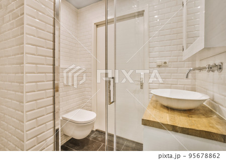 Flush toilet and shower cabin with glass partition and curtain located near sink and shelf with cosmetic products in washroom at home Flush toilet and shower cabin with glass partition and curtain located near sink and shelf with cosmetic products in washroom at home 95678862