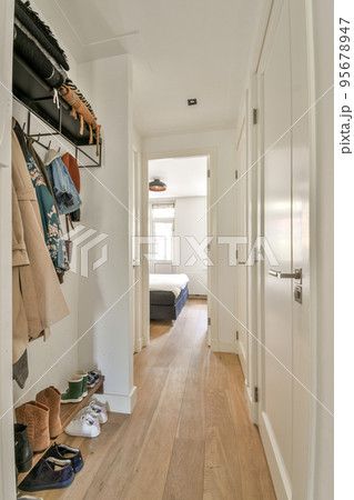 Light narrow hallway with many doors in white walls and glowing lamp over parquet floor 95678947